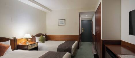 A hotel room with two beds, a desk, a chair, a TV, and a bathroom door.