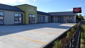 A motel with a number 319 sign, a parking lot, and a clear sky. - 319 Addington Motel (Christchurch)