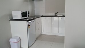 A compact kitchen with a microwave, dishwasher, and sink. - 319 Addington Motel (Christchurch)