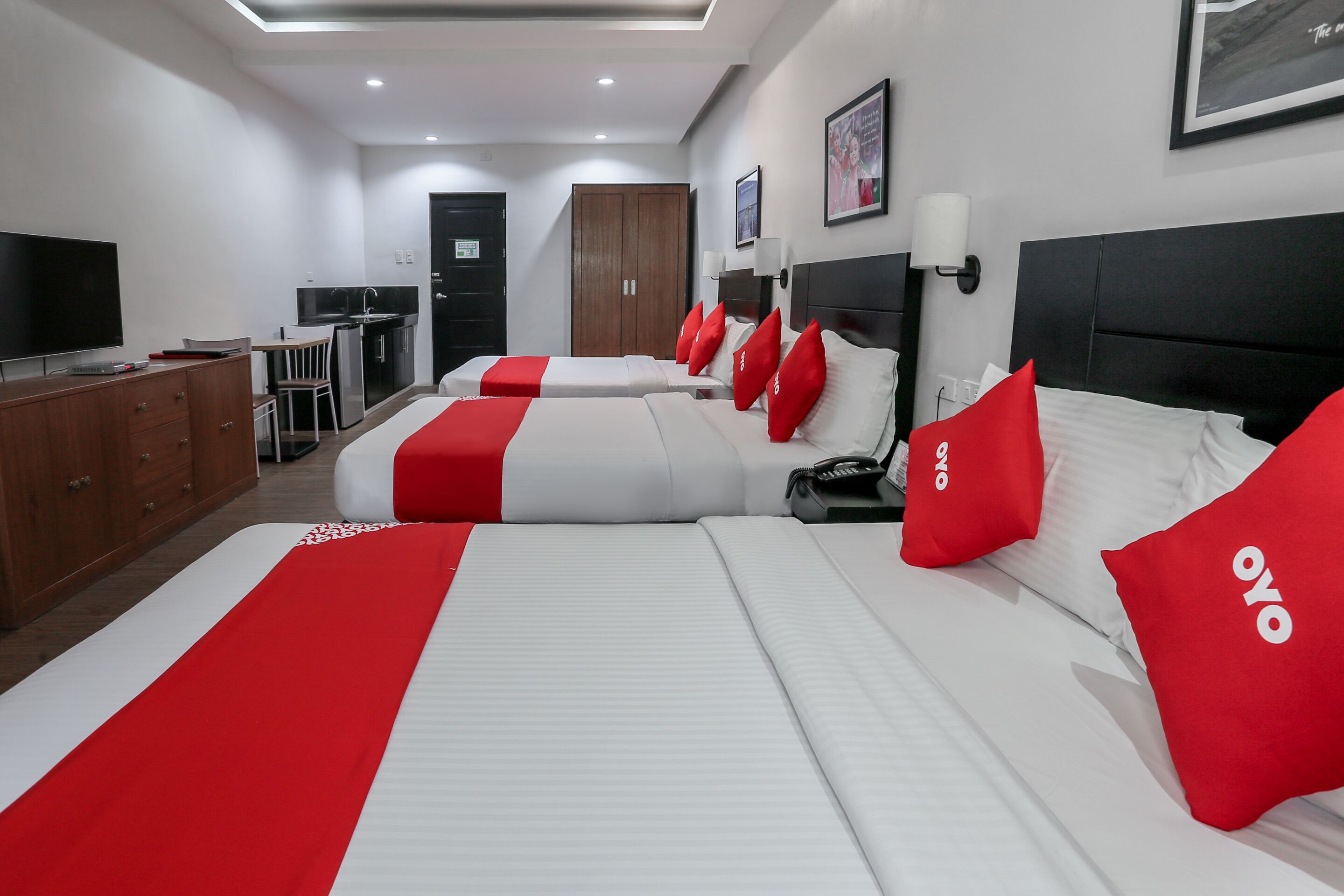 Una habitación de hotel con dos camas, un escritorio, un televisor y un armario.