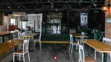 A spacious indoor venue with multiple tables and chairs, a stage with musical equipment, and a sign reading "BELIEVE WILTS."