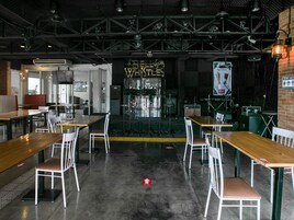 A spacious indoor venue with multiple tables and chairs, a stage with musical equipment, and a sign reading "BELIEVE WILTS."