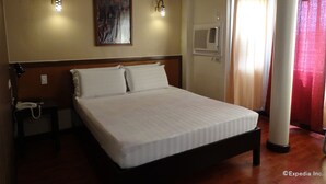 A hotel room with a bed, a nightstand, a telephone, and a wall-mounted air conditioning unit. - RueMango Apartelle and Suites (Davao)