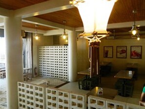 A restaurant interior with a high ceiling, pendant lighting, and a seating area with tables and chairs. - Boracay Coco Huts (Boracay Island)