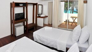 Une chambre d’hôtel avec deux lits, une télévision, un bureau et vue sur la plage.