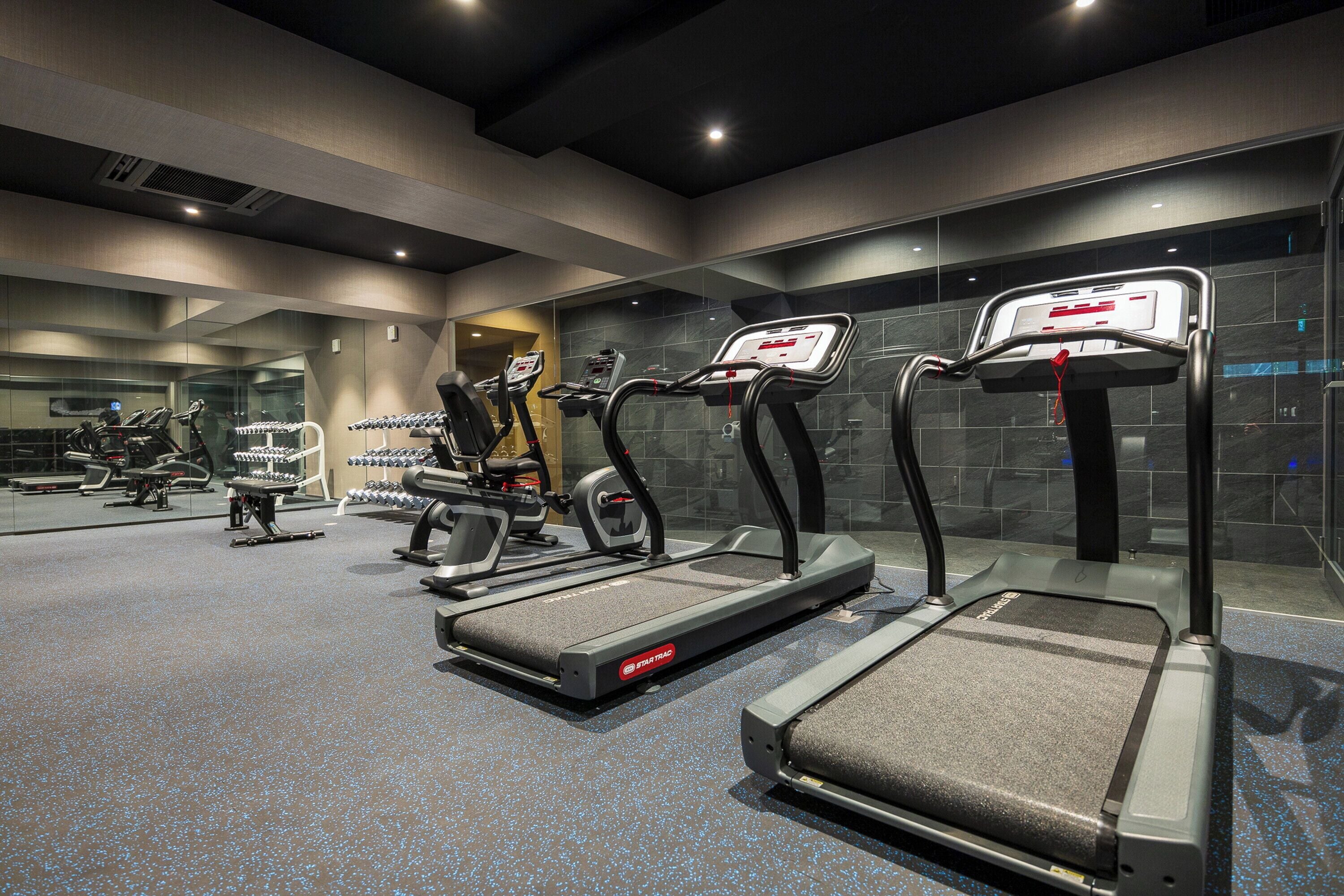 A modern gym with treadmills, stationary bikes, and weight machines.