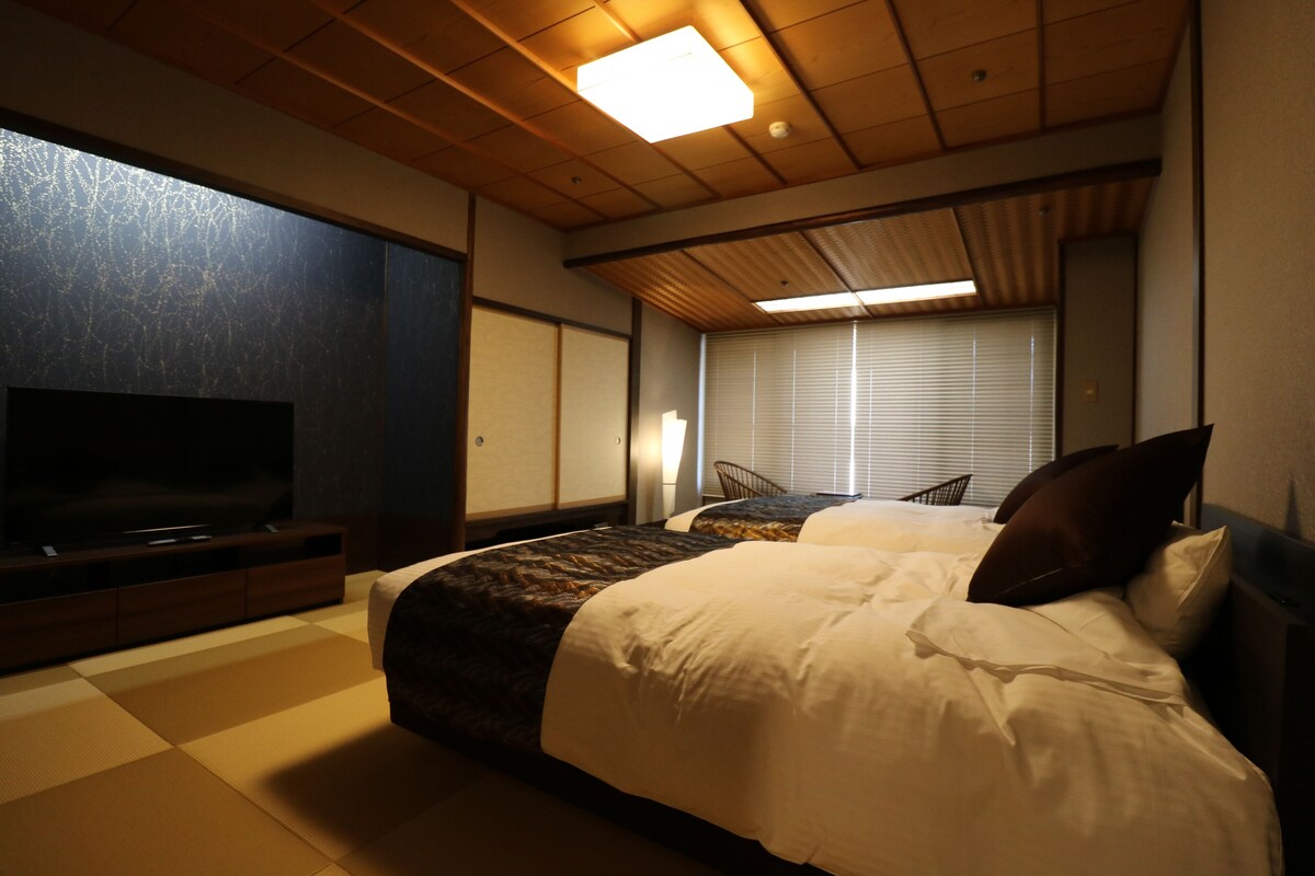 Ein Hotelzimmer mit einem großen Bett, einem Fernseher und einer traditionellen japanischen Schiebetür.
