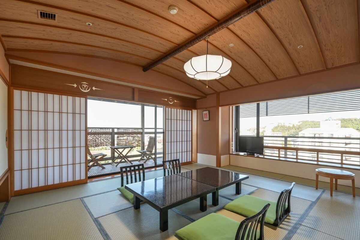 A traditional Japanese room with tatami flooring, a low table, and a view of the outside.