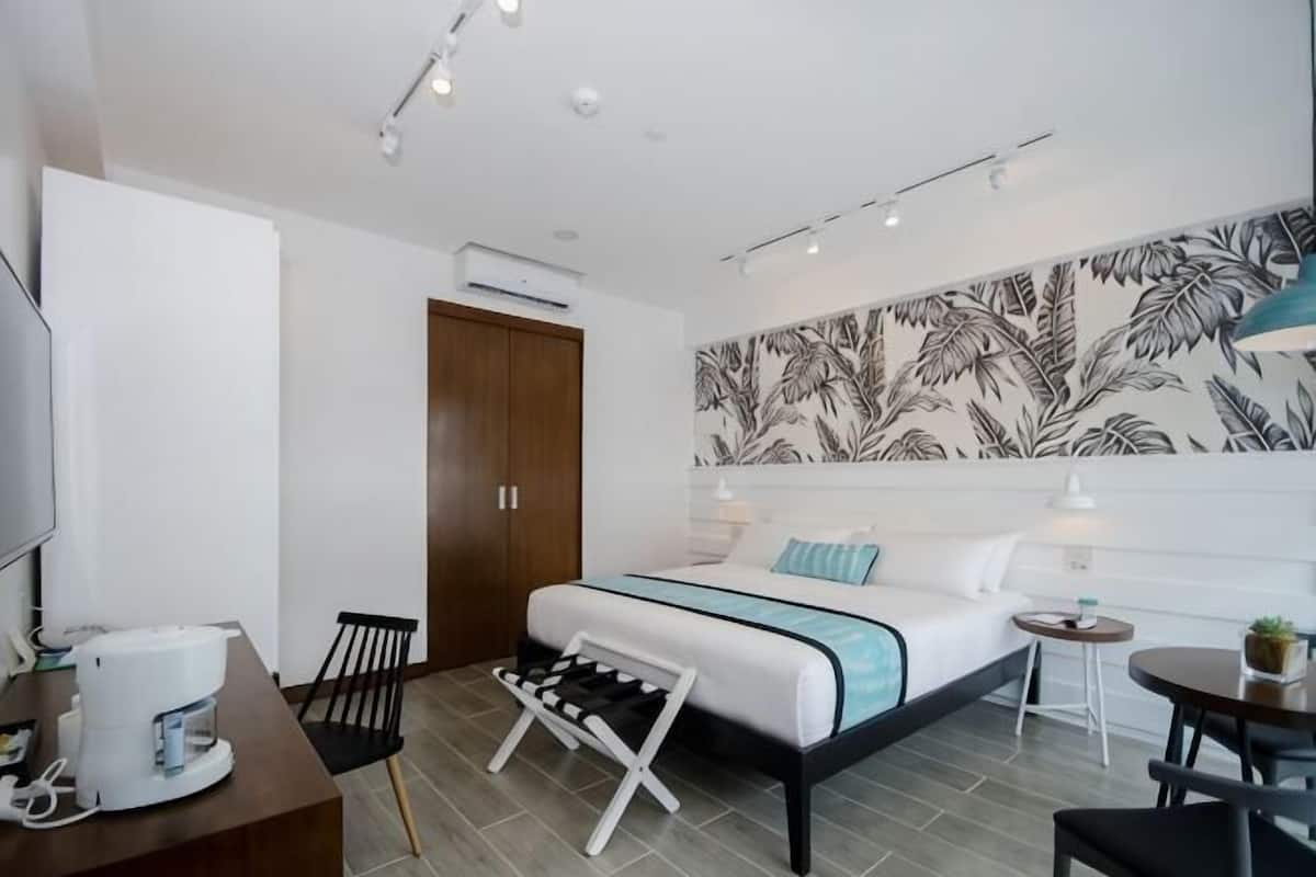 A modern hotel room with a bed, bedside tables, a desk, and a chair.