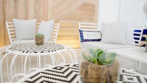 Una habitación moderna y minimalista con mobiliario blanco, una alfombra estampada y una pequeña planta en maceta.