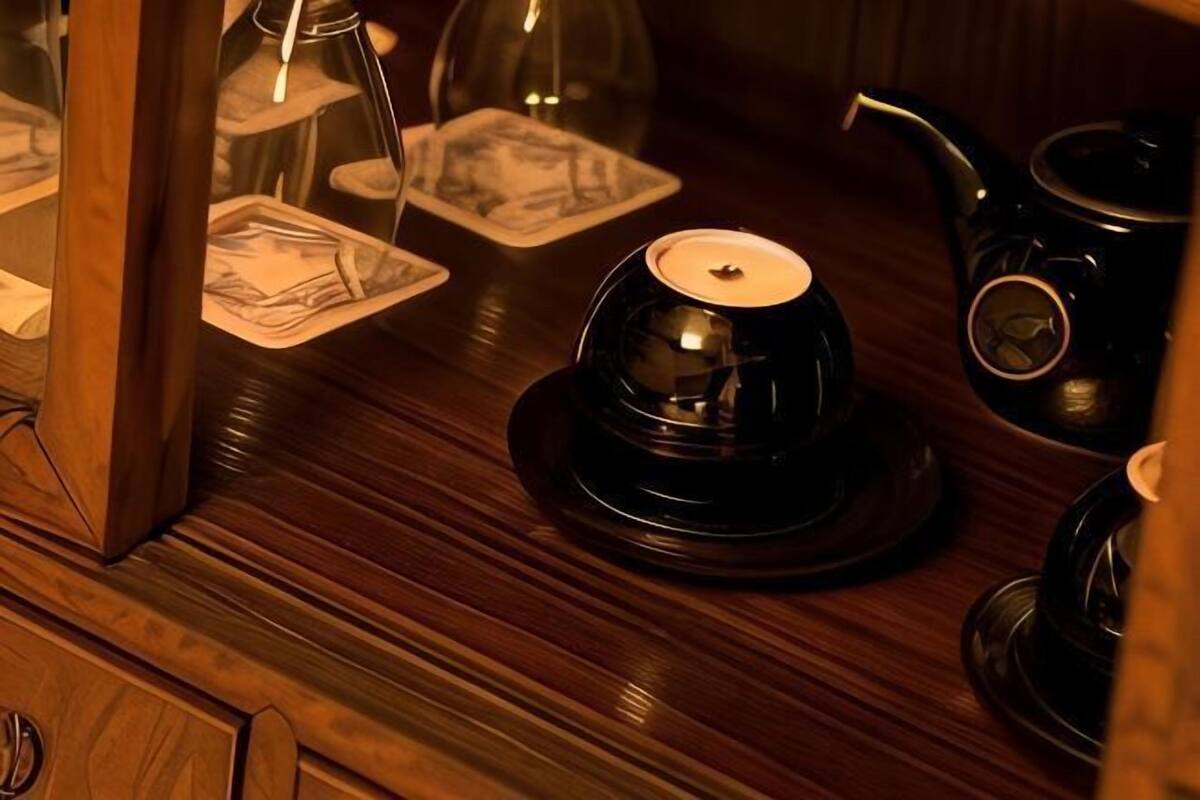 A wooden table with a tea set, including a teapot and cups, and a candle holder.