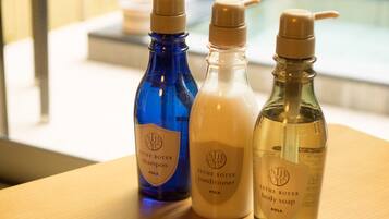 Tres botellas de productos para el cuidado corporal ESTHE ROYER sobre una mesa de madera.