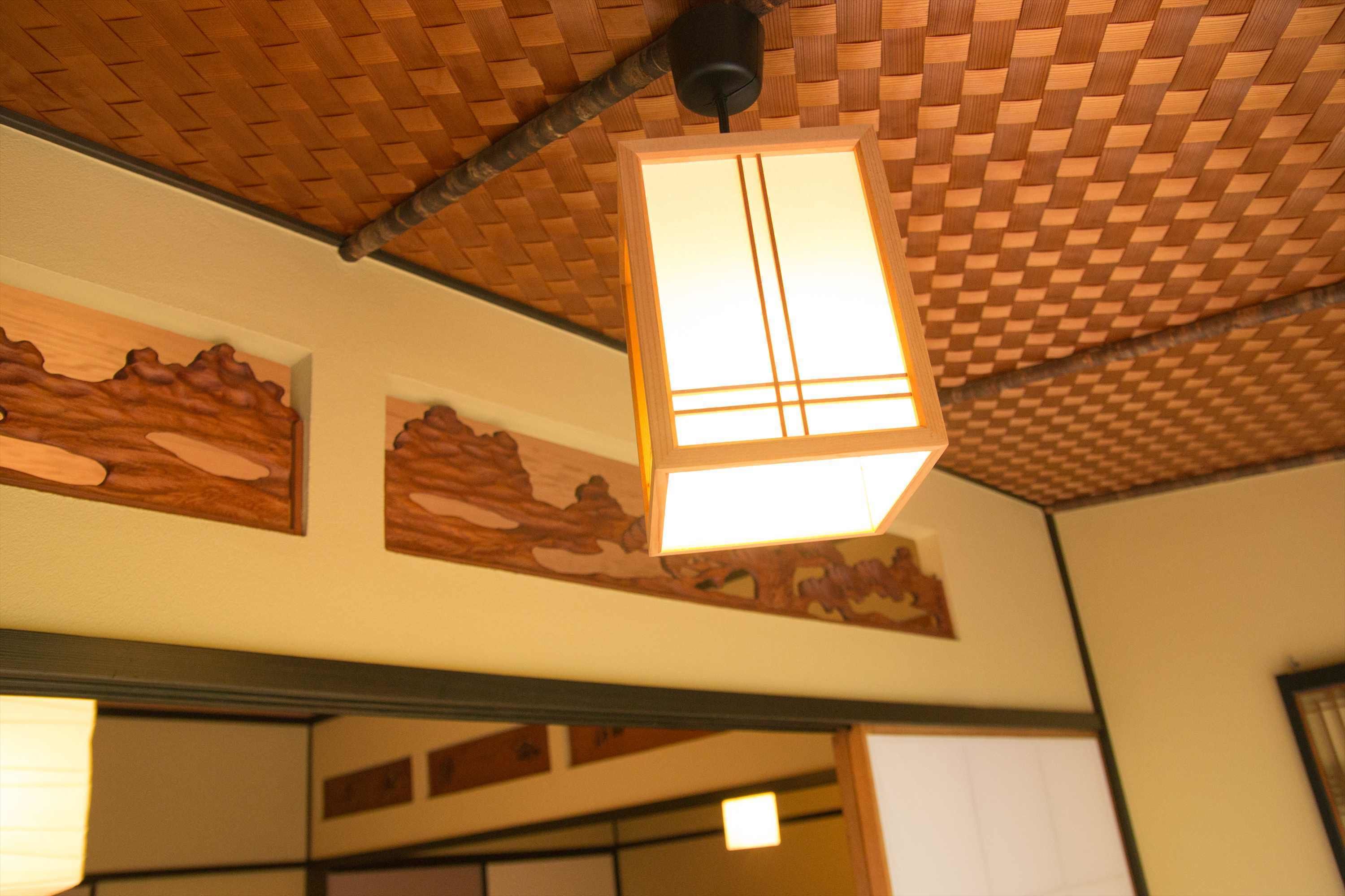 A room with a woven ceiling, a hanging light fixture, and wooden wall decorations.