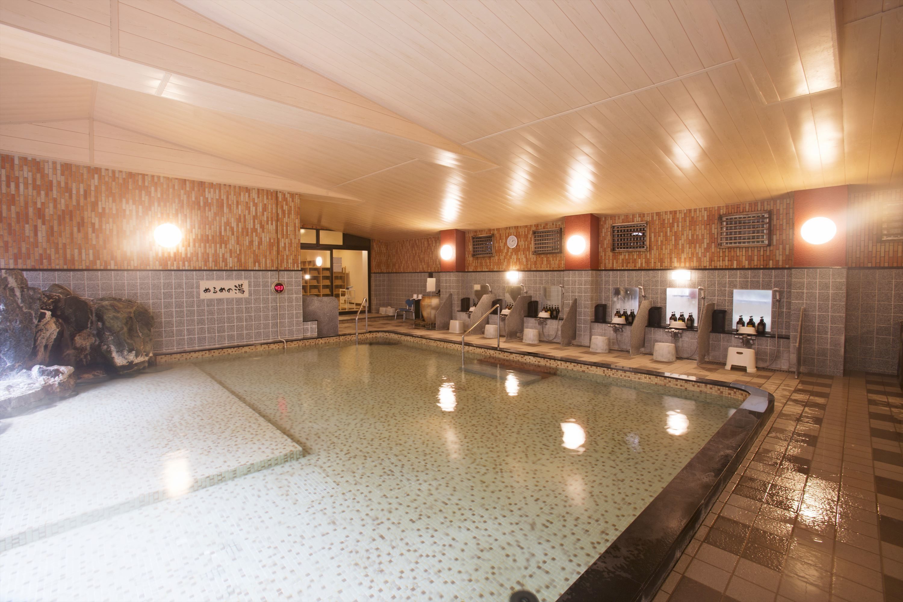 A large indoor swimming pool with tiled walls and a wooden ceiling.