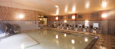 Una gran piscina interior con paredes de azulejos y techo de madera.