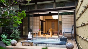 Et traditionelt japansk rum med tatamimåtter, et lavt bord og en skydedør til et privat område.