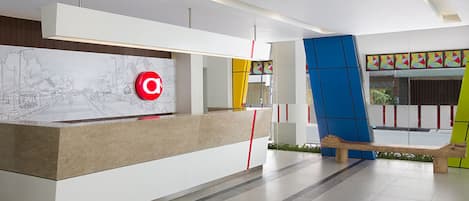 A modern reception desk with a red logo, a map, and a bench.