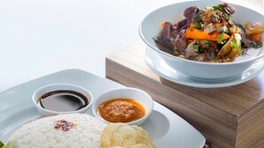 Un repas composé de riz, d’un bol de ragoût de légumes et de viande, et de deux petits bols de sauce.