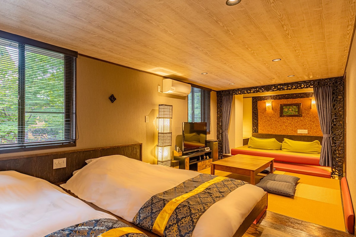A hotel room with two beds, a television, a desk, and a sofa.