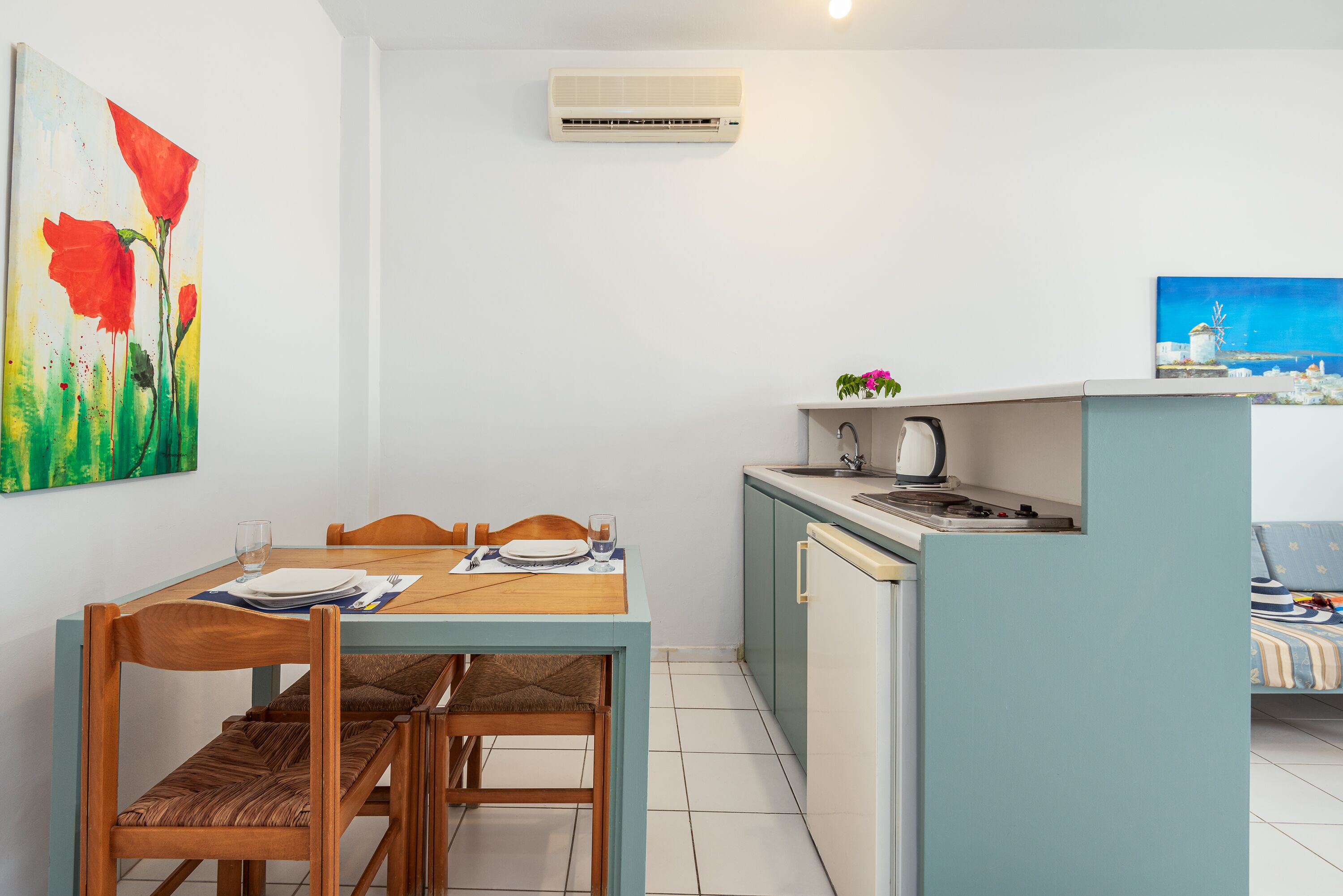 A compact kitchen with a dining area, a small island, and a bed with a striped bedspread.