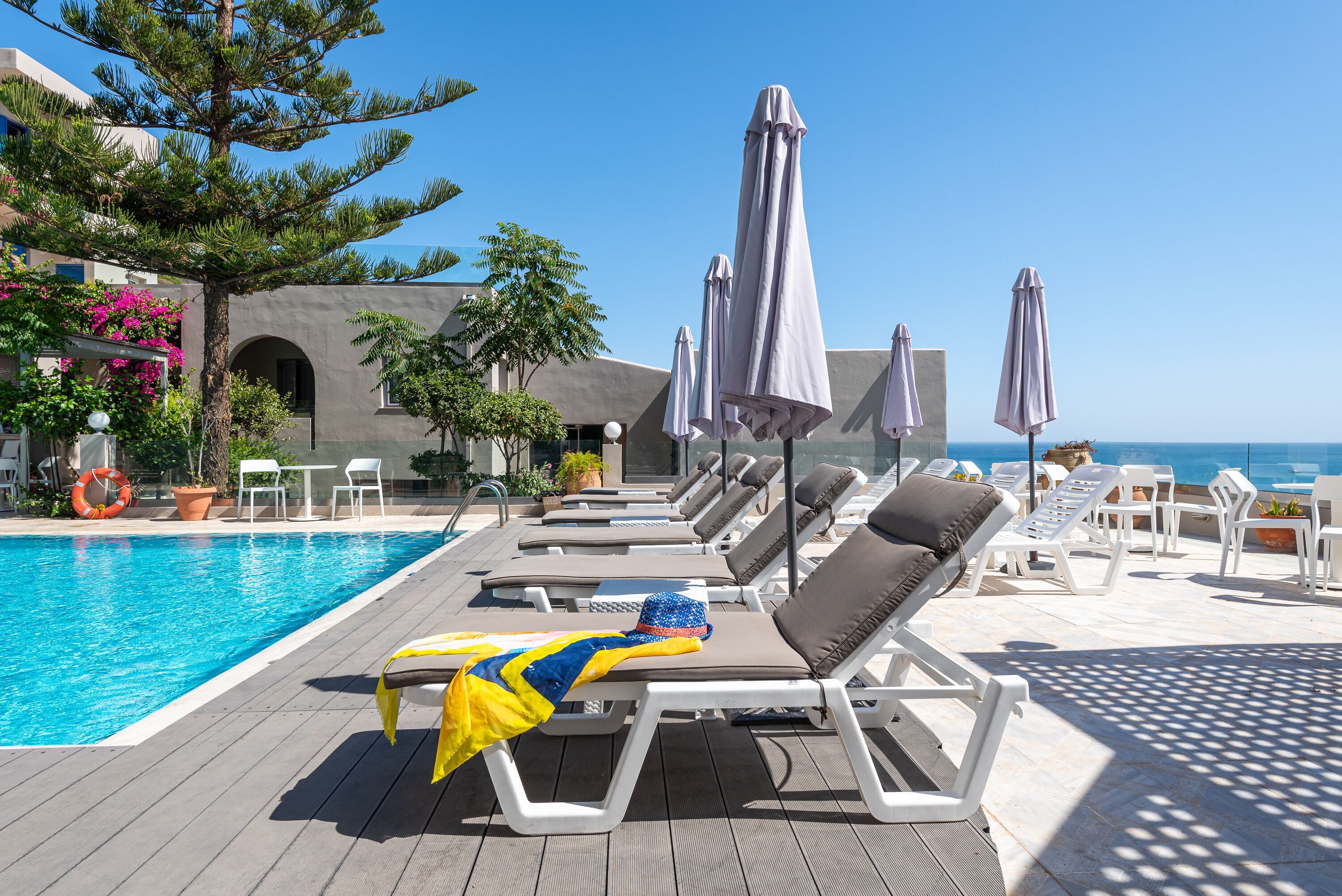 A poolside area with lounge chairs, umbrellas, and a view of the ocean.