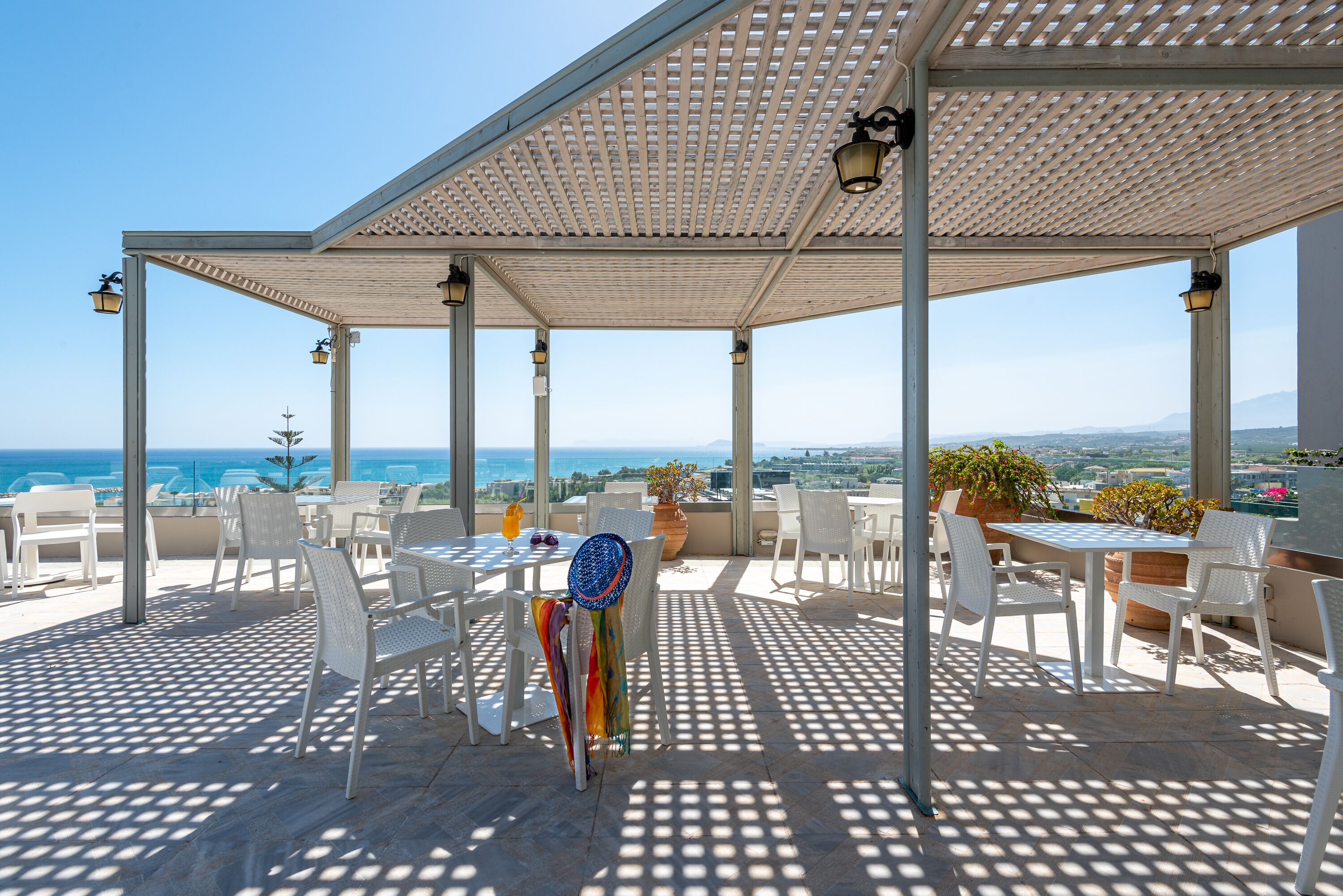 Eine Außenpatio mit weißen Möbeln, einer Pergola und Blick auf das Meer.