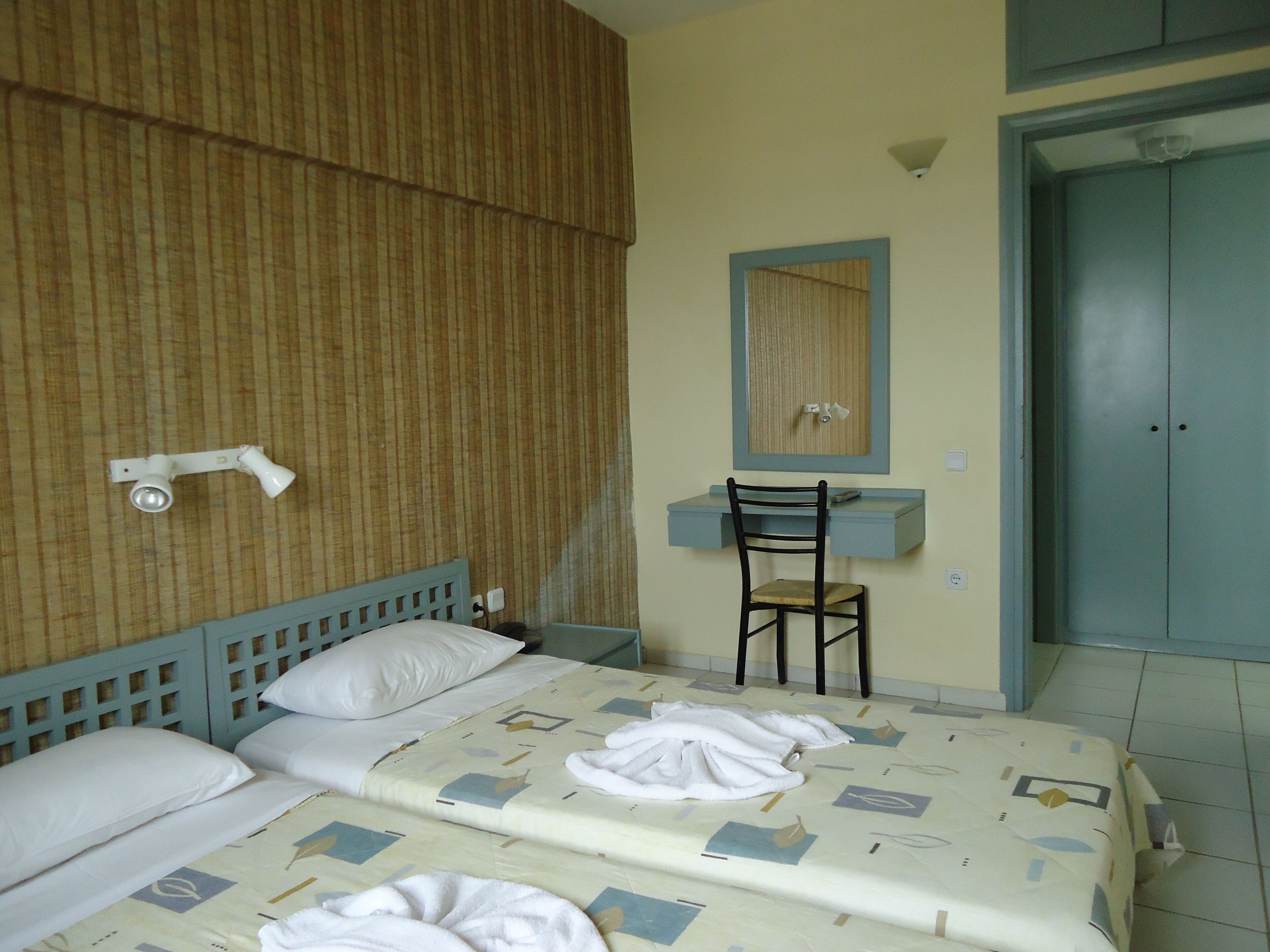 A hotel room with a bed, a chair, a desk, and a wardrobe.