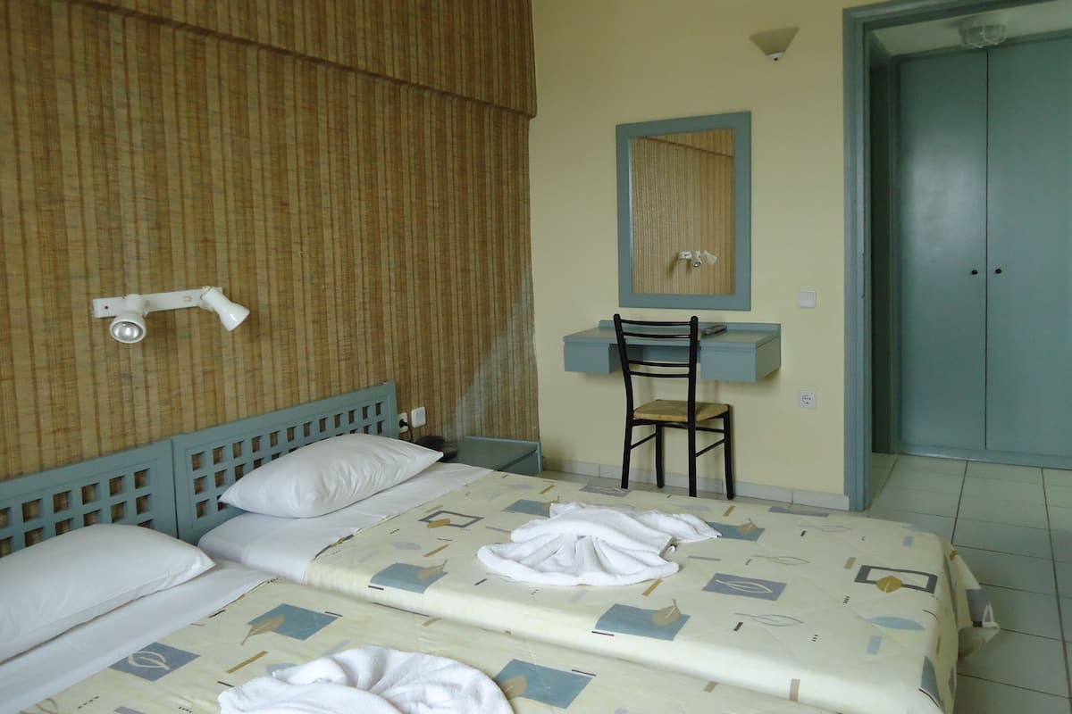 Una habitación de hotel con cama, una silla, un escritorio y un armario.