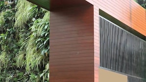 A modern building with a wooden facade and a green wall with plants. - Serene Residence (Kanchanaburi)