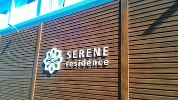 A wooden facade with the text "SERENE residence" and a stylized flower logo.