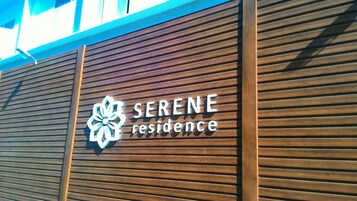 A wooden facade with the text "SERENE residence" and a stylized flower logo.