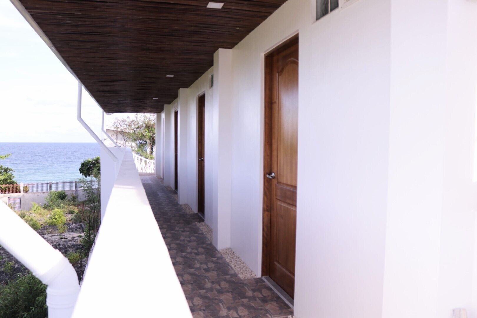 A corridor with a view of the sea, leading to a wooden door.