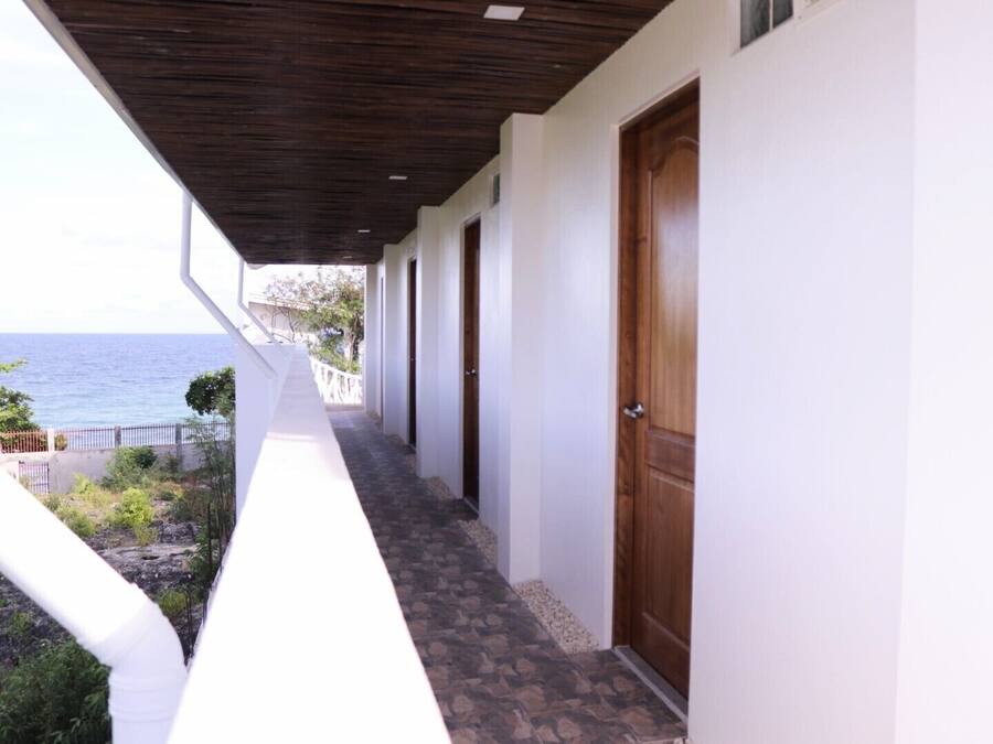 A corridor with a view of the sea, leading to a wooden door.
