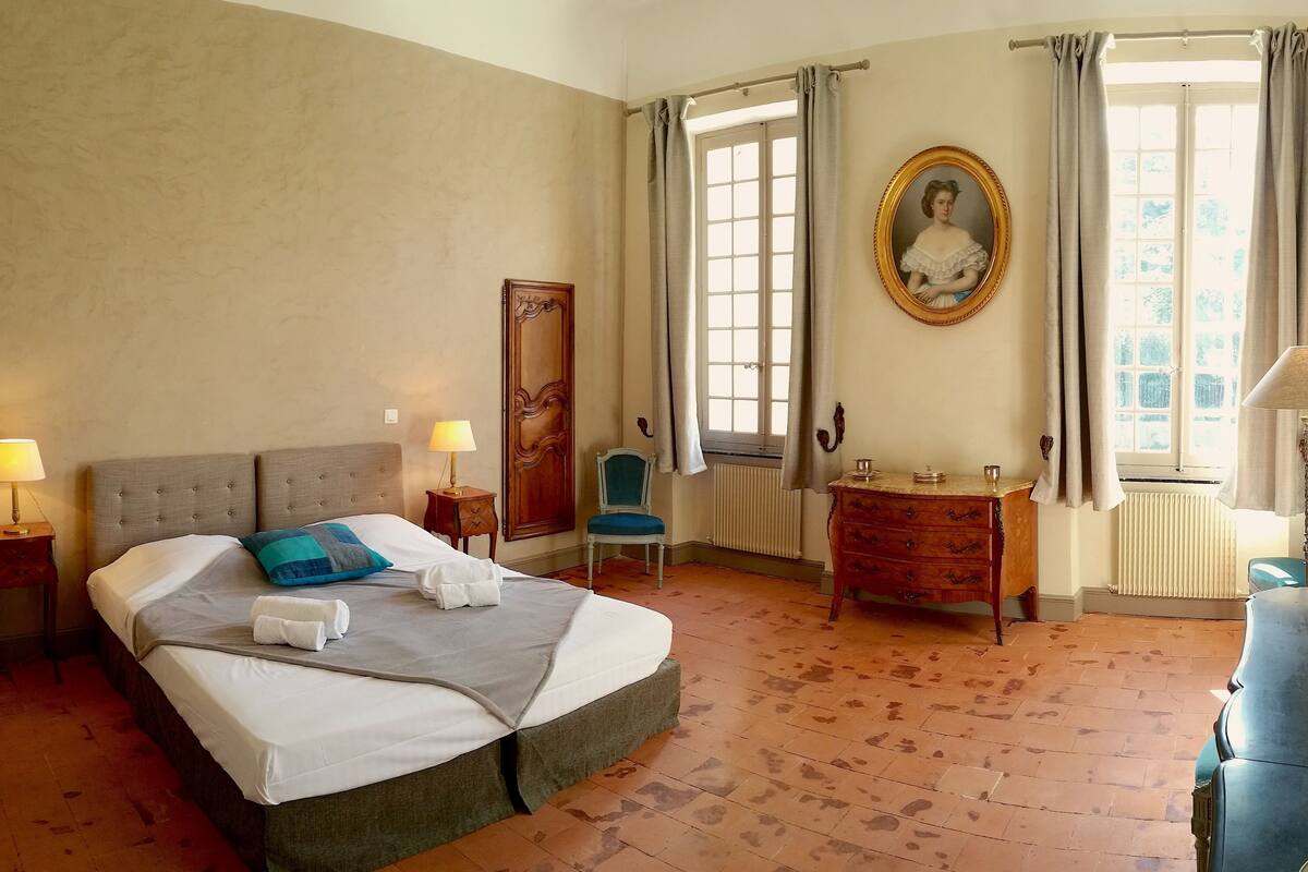 Une chambre d’hôtel avec un grand lit, une commode, une chaise et un tableau au mur.