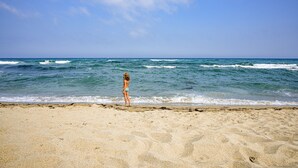 Een strand met iemand die aan het water staat.