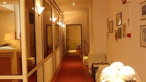 Um corredor de hotel com um longo hall, paredes espelhadas e uma área de estar com mesa e cadeiras.