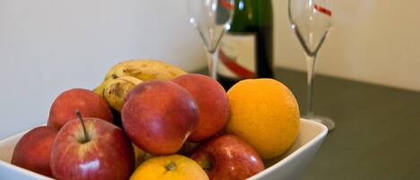 A bowl of fruit with apples and oranges on a table.
