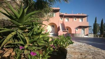 Un edificio moderno con fachada rosa, una entrada arqueada y un camino de piedra que conduce a la entrada.