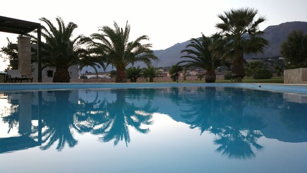 A clear swimming pool with reflections of palm trees and a mountain in the background. - Kallicrates Village (Sfakia)