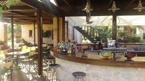 Un espace bar doté d’un comptoir en pierre, de plusieurs tabourets et d’une variété de bouteilles.