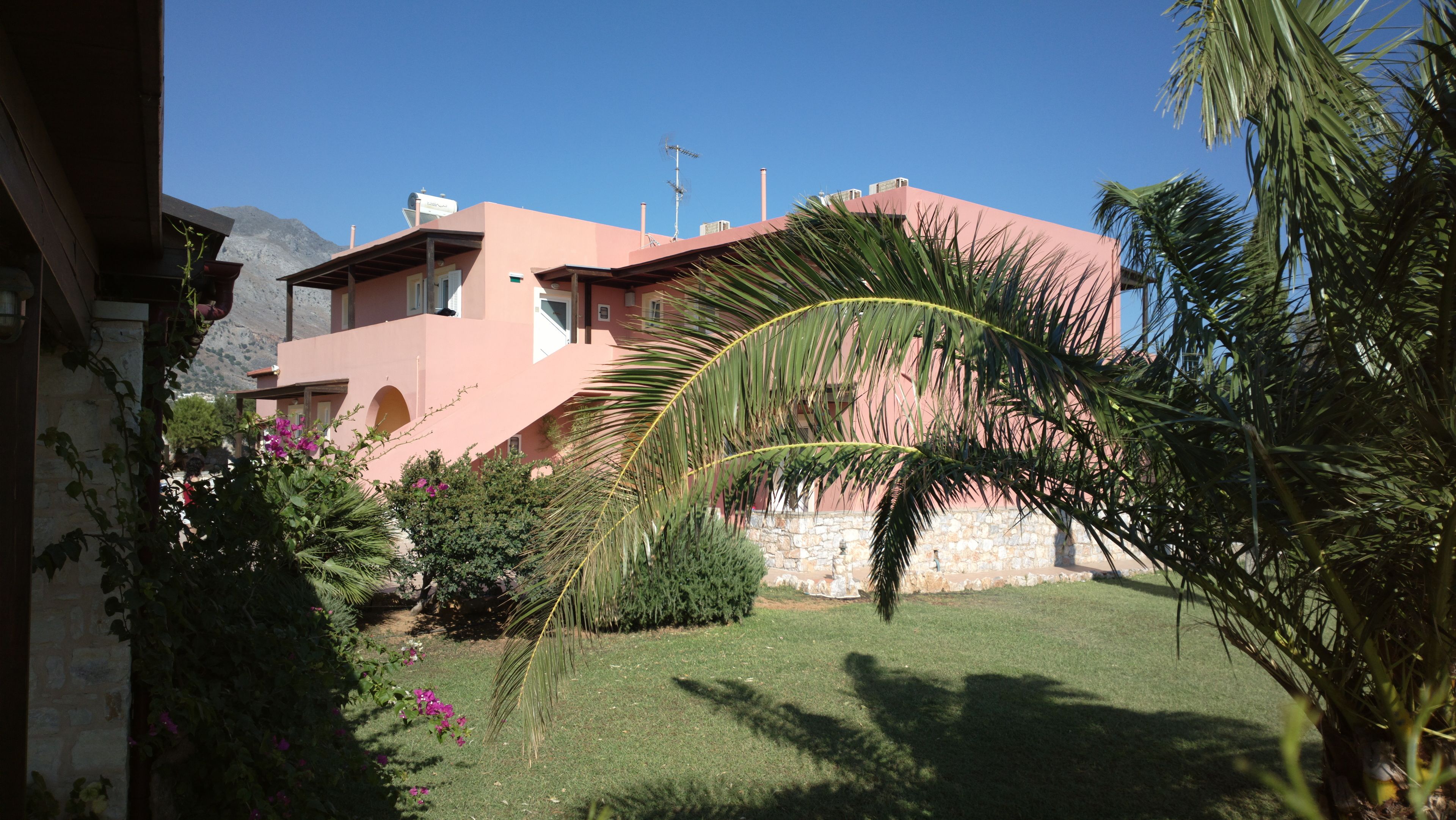 A pink building with a stone wall and a grassy yard.