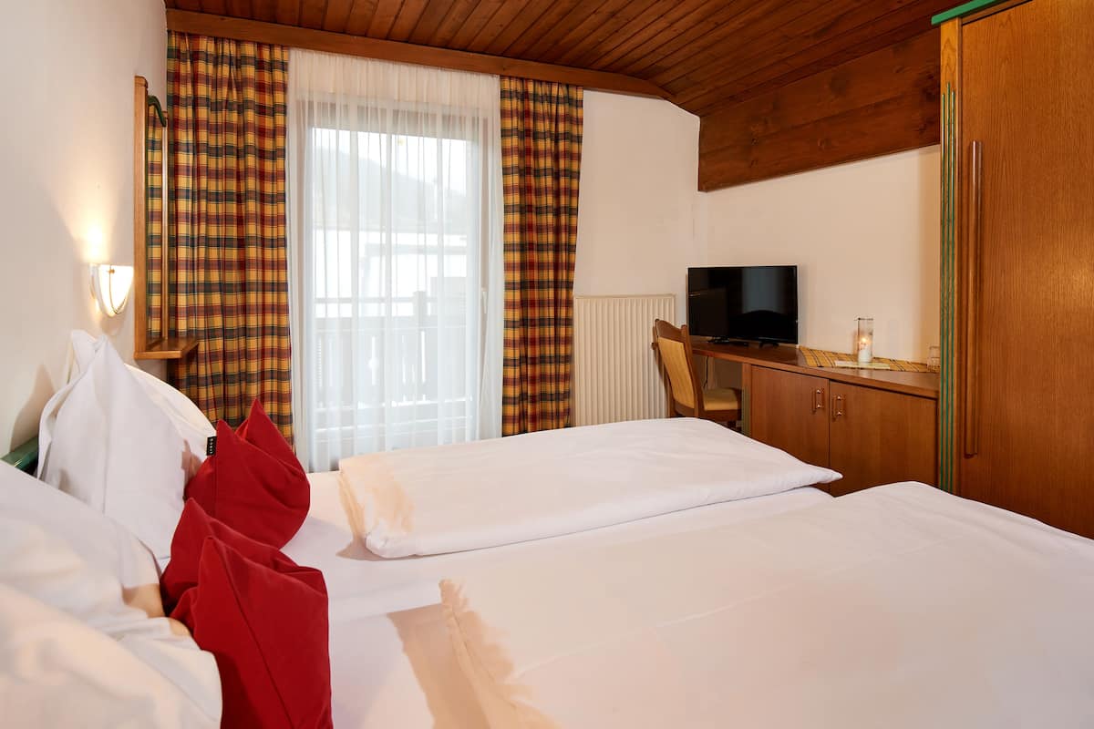 Une chambre d’hôtel avec deux lits, une télévision, une armoire en bois et un bureau.