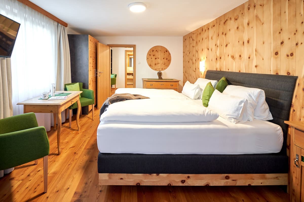 Une chambre avec un grand lit, un bureau et deux chaises.