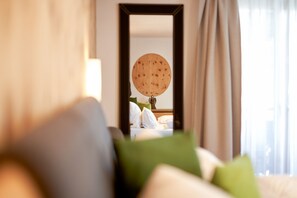 Een hotelkamer met een bed, kussens, een spiegel en een raam met gordijnen.