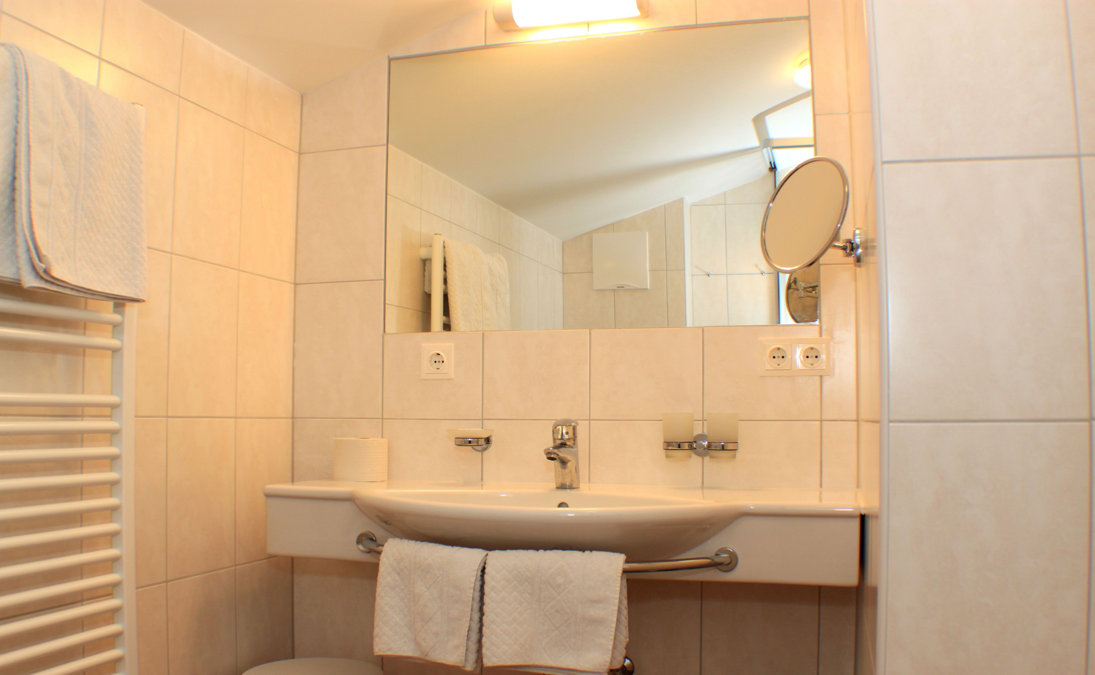 Une salle de bain avec un lavabo blanc, un miroir et un porte-serviettes.