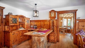 Una cocina rústica con armarios de madera, una isla central y un comedor con sillas de madera.
