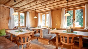 Una cabaña de madera acogedora con comedor, asientos y ventanas amplias.