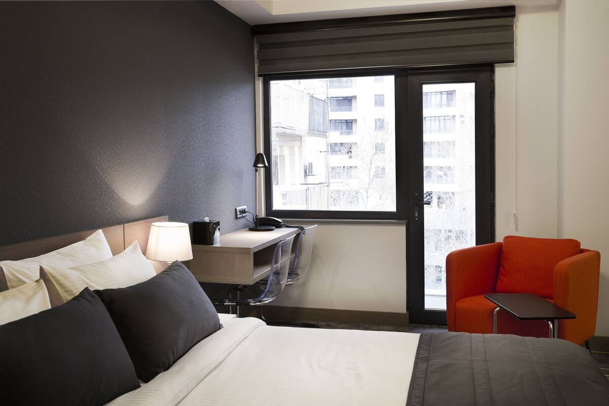 Une chambre d’hôtel avec un lit, un bureau et une chaise.