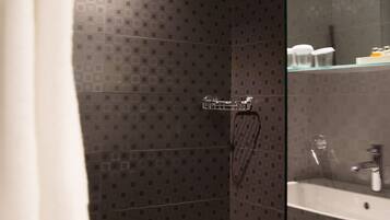 Un bany modern amb una cabina de dutxa de vidre, un lavabo blanc i un porta tovalloles.