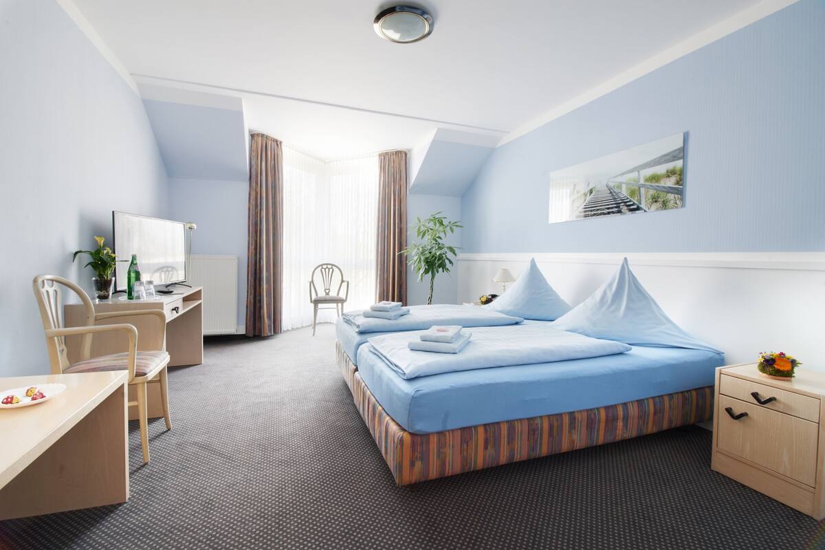 Een hotelkamer met een bed, bureau, stoel en uitzicht op een trap.